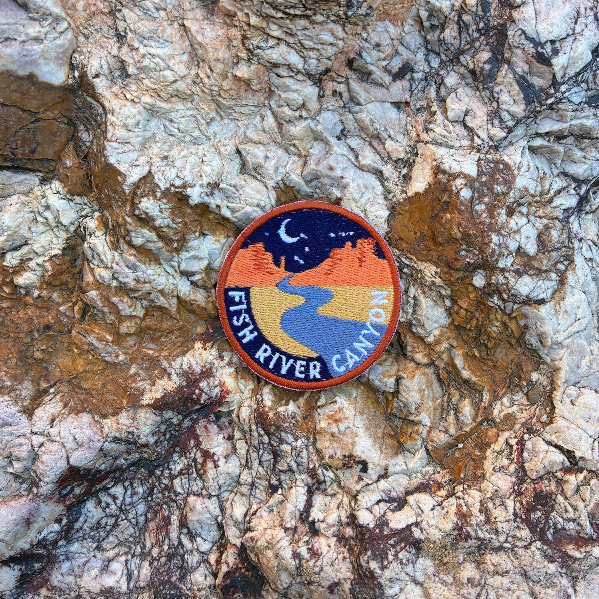 Round patch with 'Fish River Canyon' design on a textured rock surface